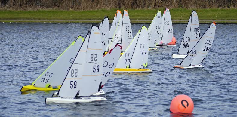 A radio controlled sailboat heeling upwind with its sails full