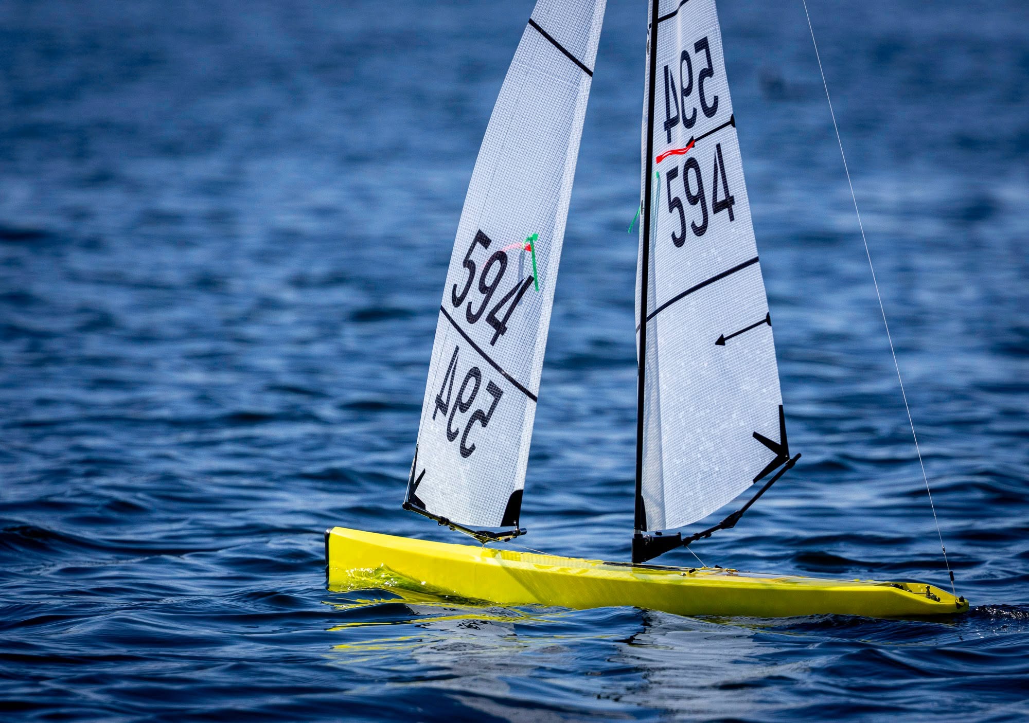 Two radio controlled sailboats sailing away from the camera